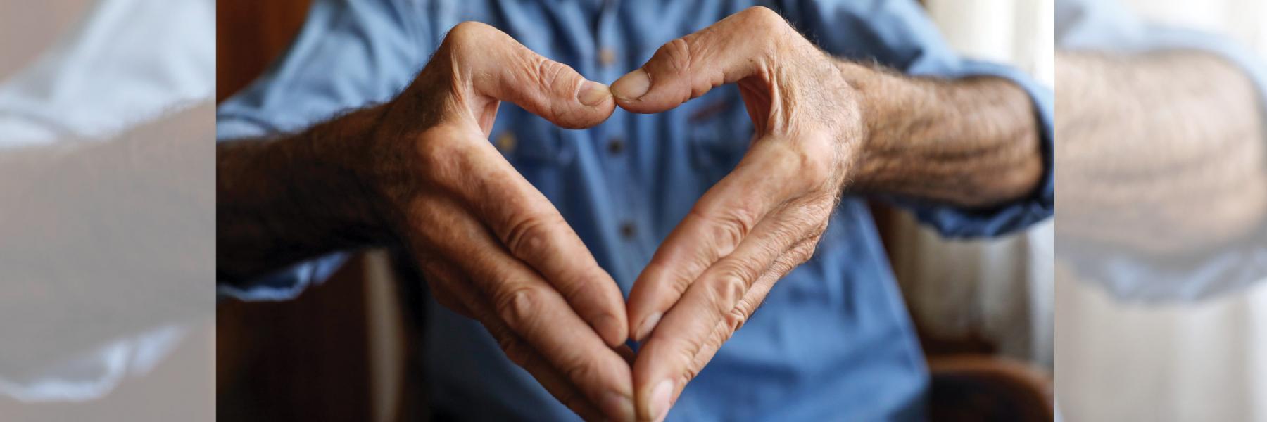the shape of a heart, formed by the hands of an elderly man