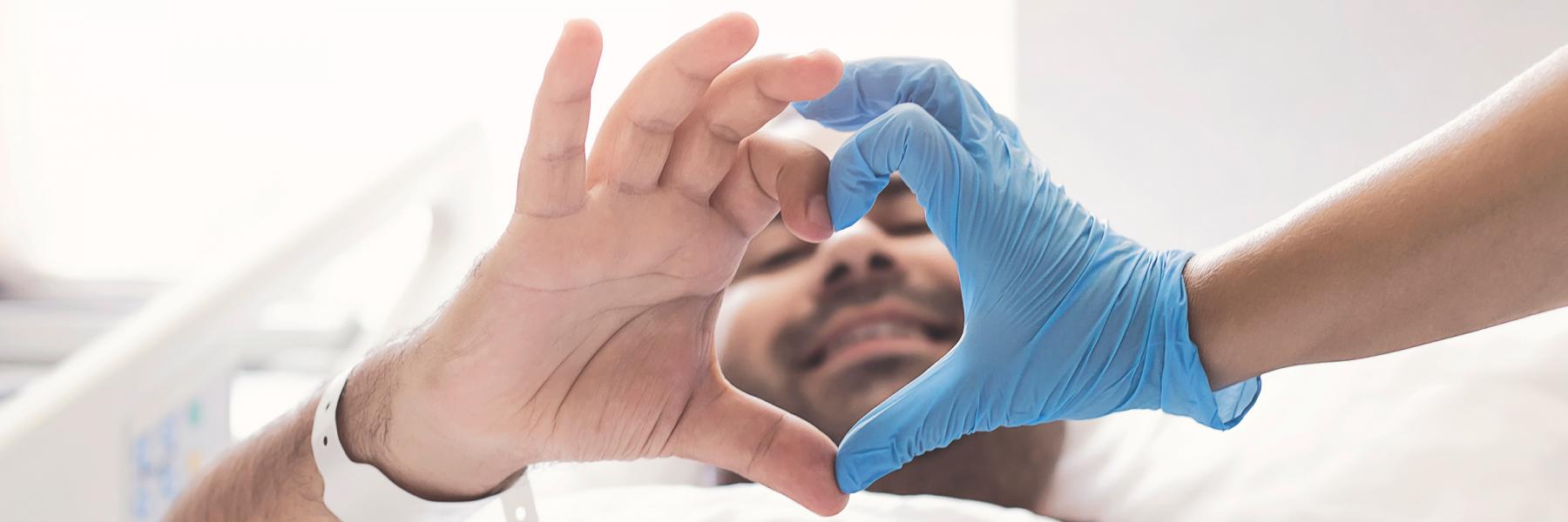 image of transplant surgery patient making heart hand symbol with doctor