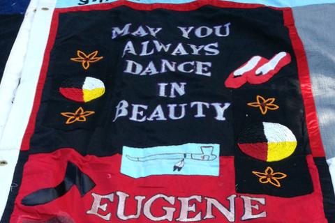 Red and black AIDS quilt panel with ballet shoes, peace pipe, stars and moon