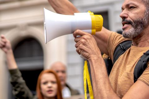 picture of a black man yelling into a bullhorn during a political protest