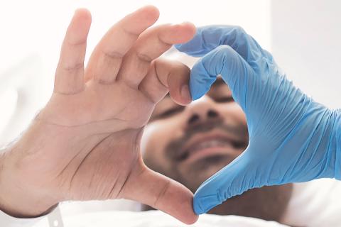 image of transplant surgery patient making heart hand symbol with doctor